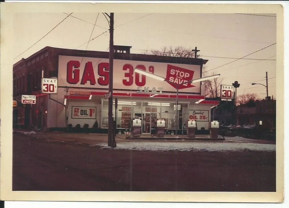 The SKAT service station photographed from the street corner at dusk, streetlight overhead.
